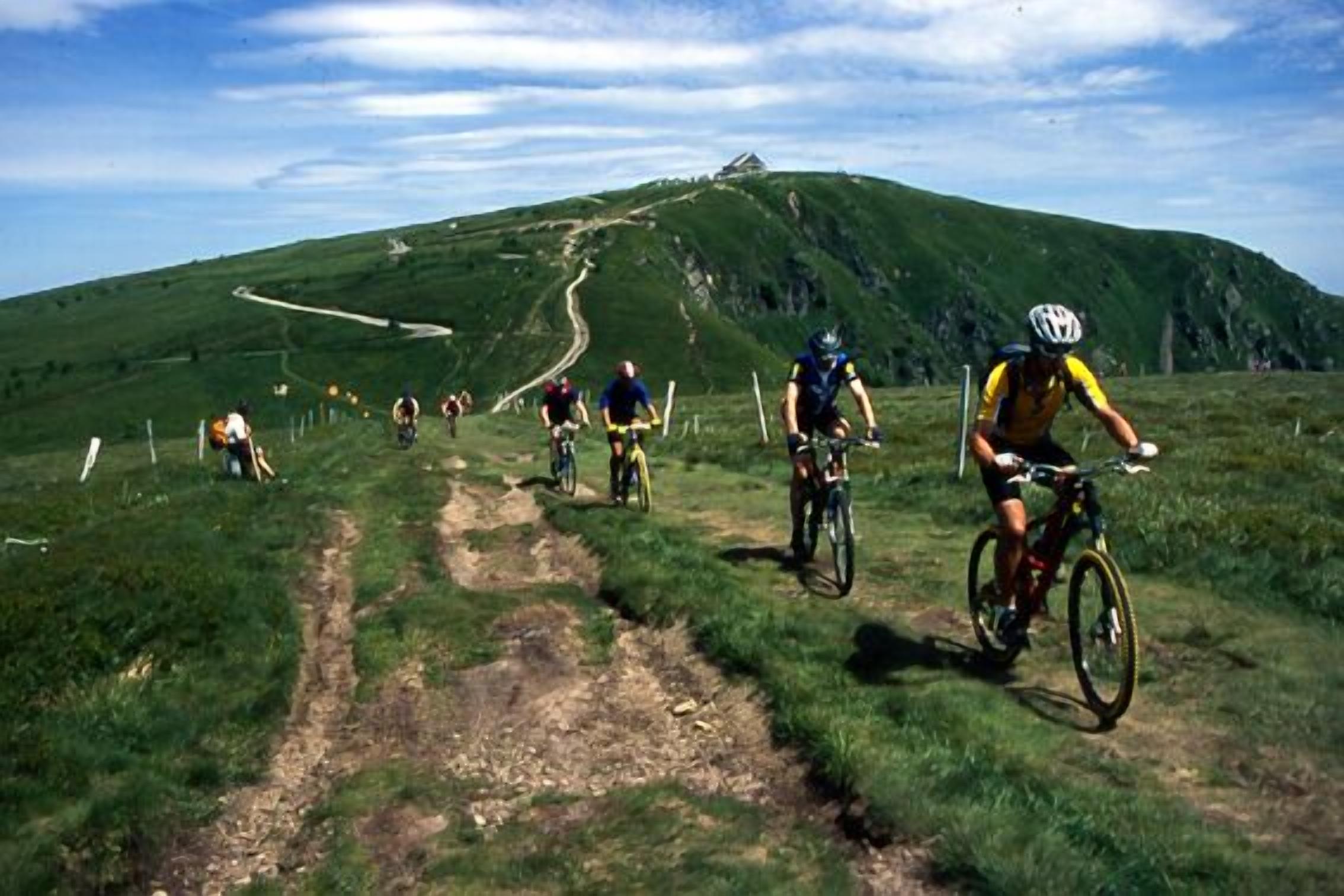 A group of cyclists on a mountain trail with a clear sky.