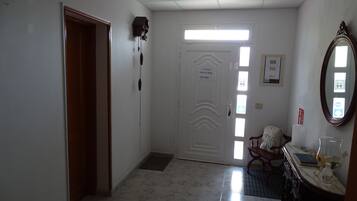 Un pasillo con una puerta blanca, un letrero de recepción, un espejo y una zona de lavamanos.