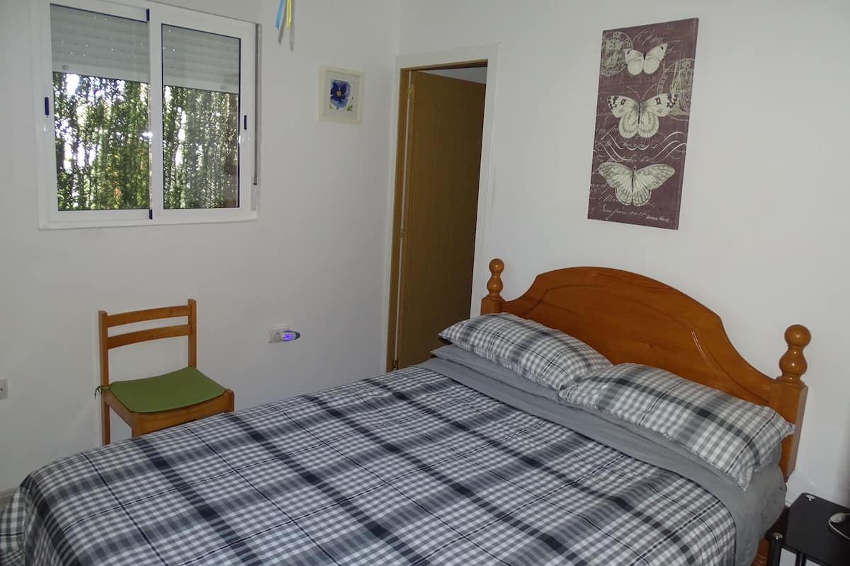A bedroom with a bed, a chair, a window, and a door.