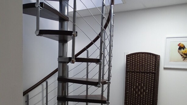 Una escalera en espiral con barandillas de metal y suelo de baldosas.