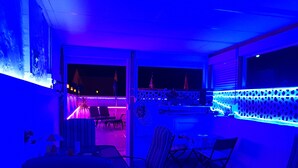 Una habitación con vistas al mar, un balcón con barandilla y una mesa con sillas.