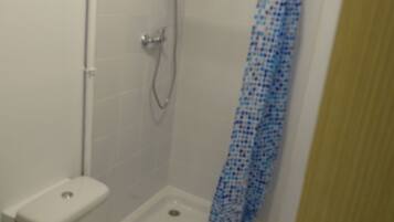 A small bathroom with a toilet, a shower stall, and a shower curtain.