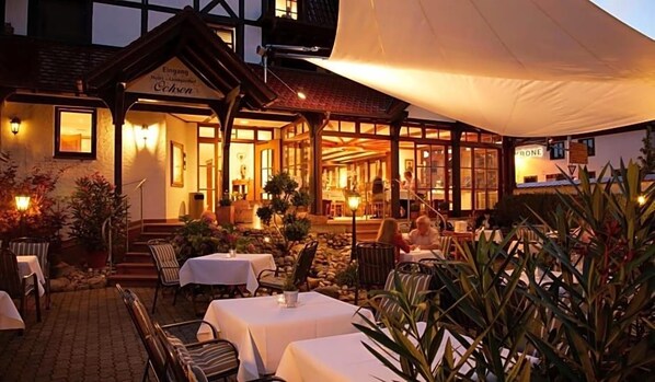 Un restaurante con terraza al aire libre, un porche cubierto y fachada de piedra.