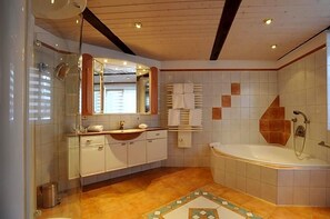 A bathroom with a bathtub, a glass shower enclosure, and a vanity with a mirror.