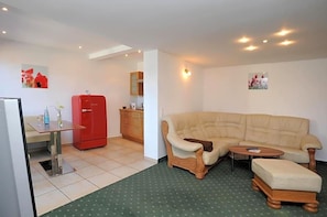 A compact living space with a kitchenette, a sofa, a small table, and a red refrigerator.