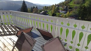 Een balkon met een tafel en stoelen, met uitzicht op een prachtig landschap met huizen en bomen.