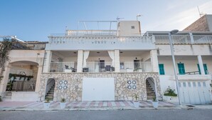A two-story building with a balcony, stone facade, and a white garage door. - Beautiful apartment for 4 guests with A/C, WIFI, TV and patio (Alcúdia)