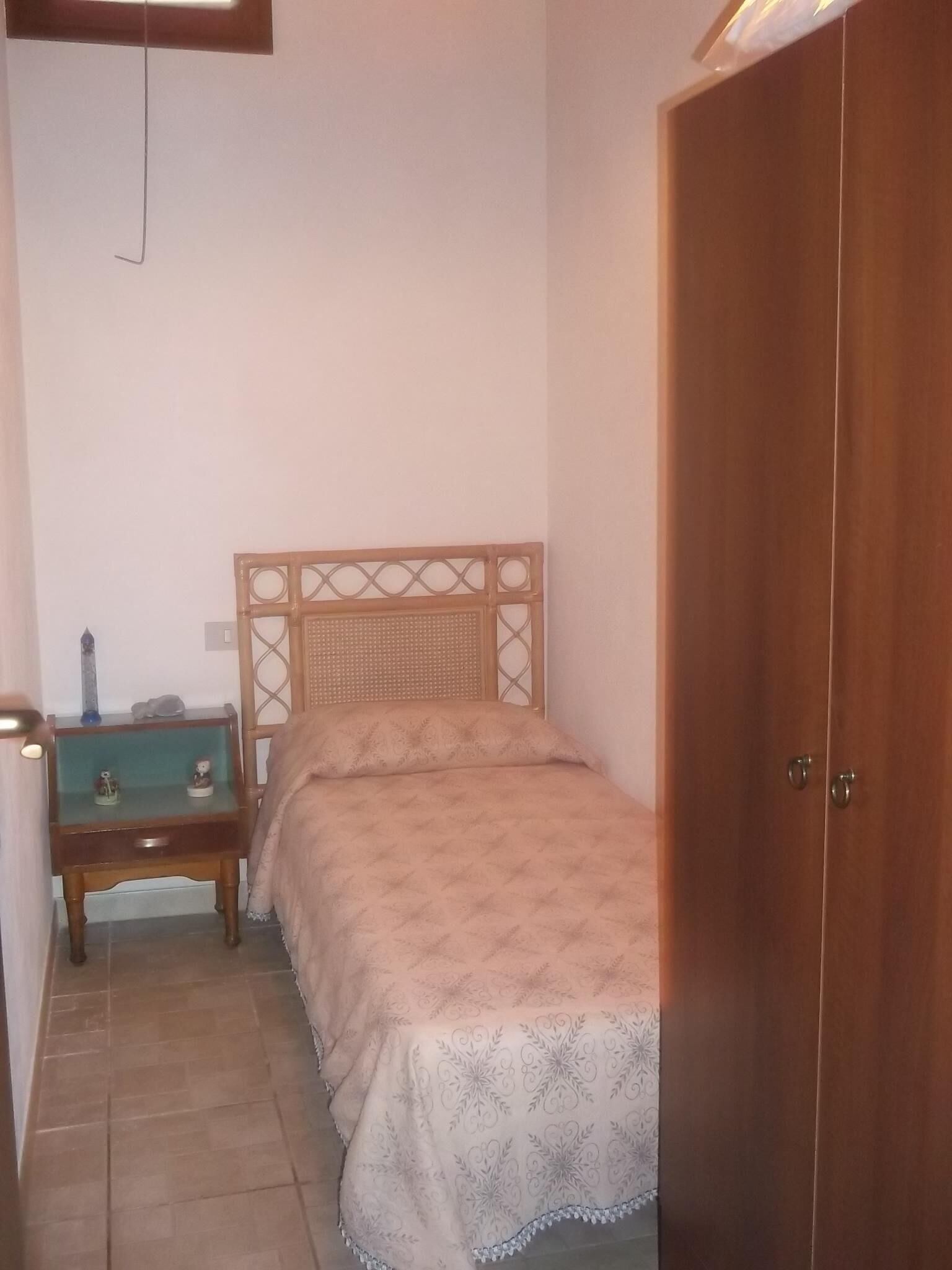 Una camera da letto con un letto di legno, un comodino con una lampada e un armadio.