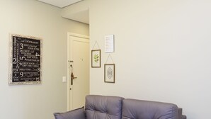 Ein modernes Wohnzimmer mit grauem Sofa, einer Wand mit motivierenden Zitaten und Einbau-Deckenleuchten.