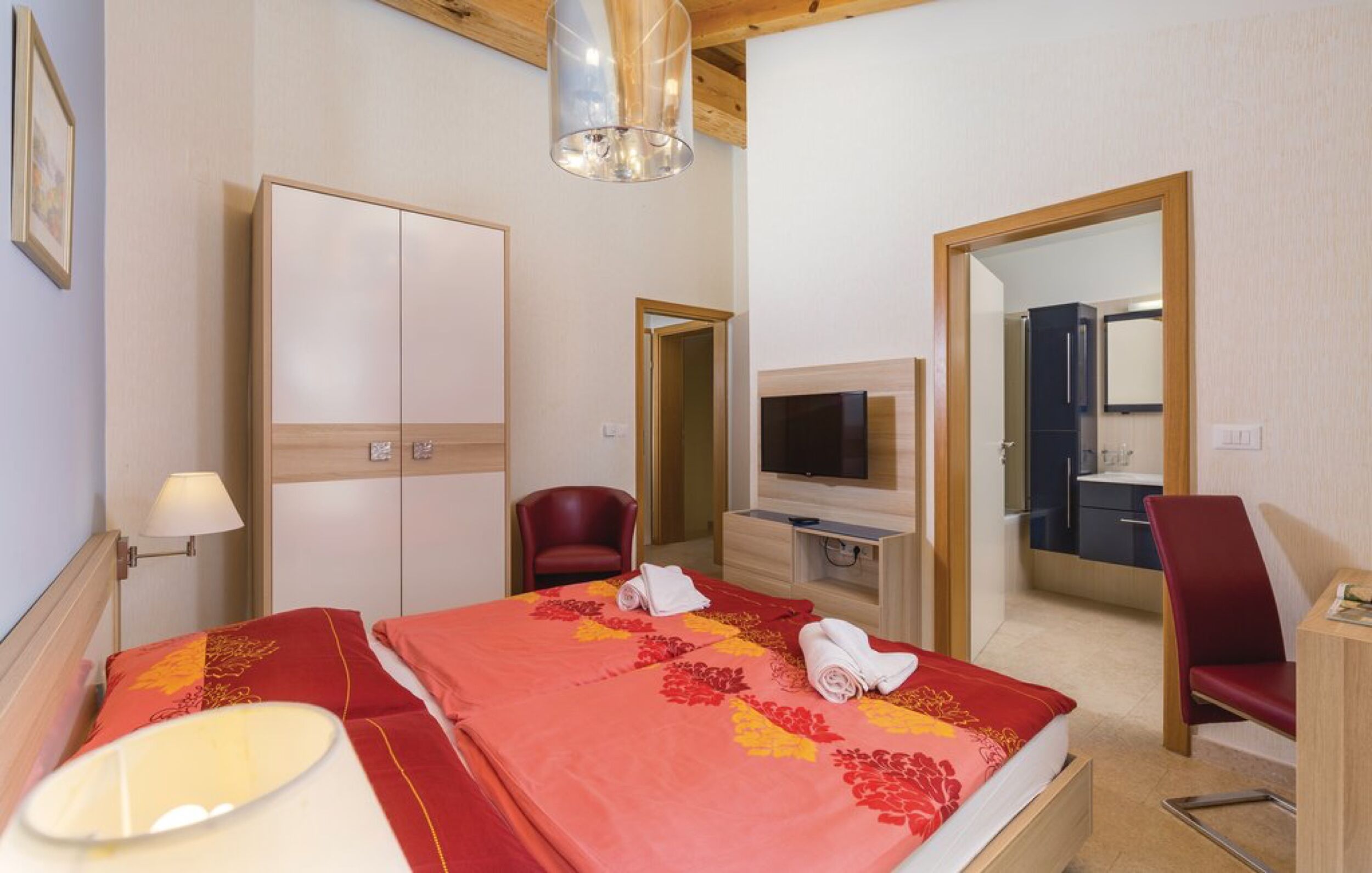 Een hotelkamer met een bed, televisie, bureau en stoel.