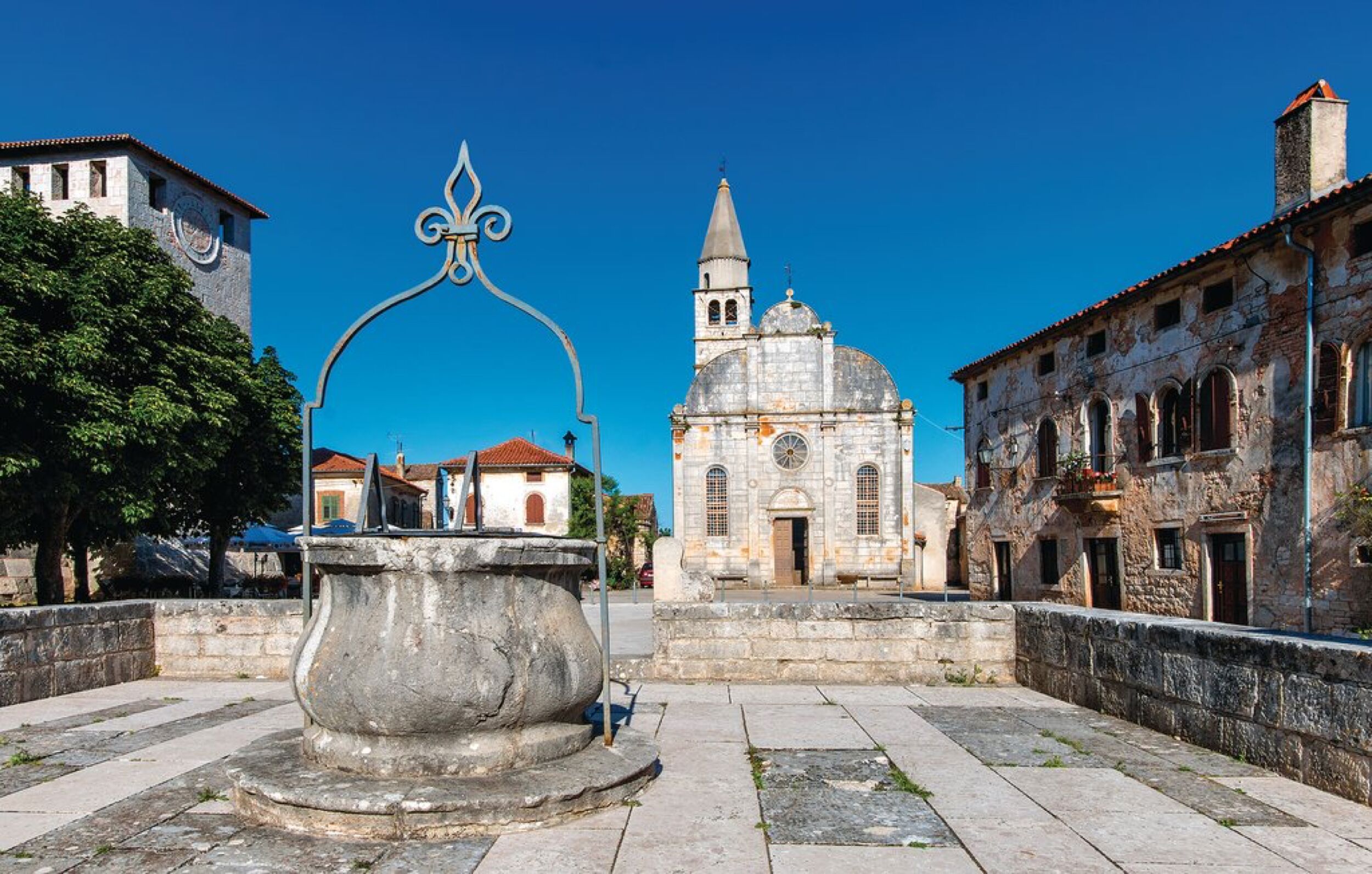 A historic square with a fountain, a church, and traditional buildings.