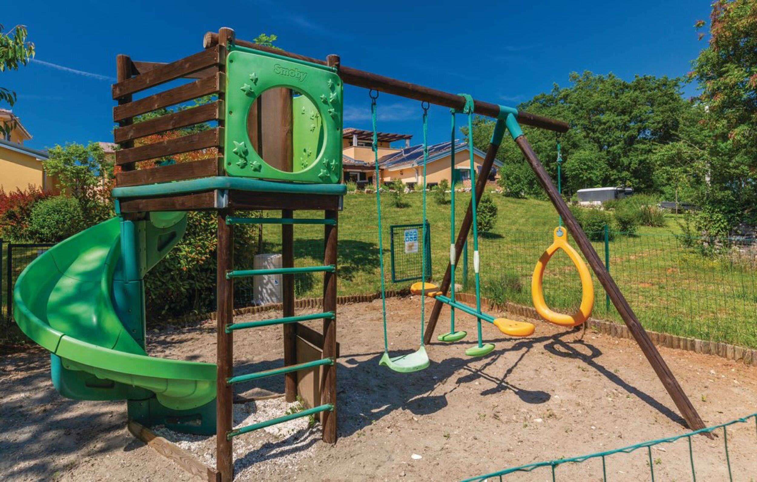Un’area giochi con uno scivolo, altalene e una struttura per arrampicarsi.