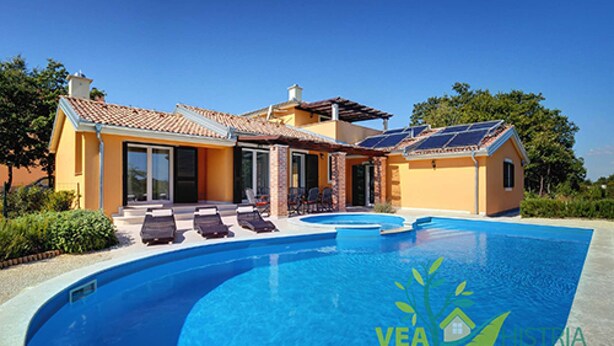 A modern house with a swimming pool, solar panels, and a patio with lounge chairs.