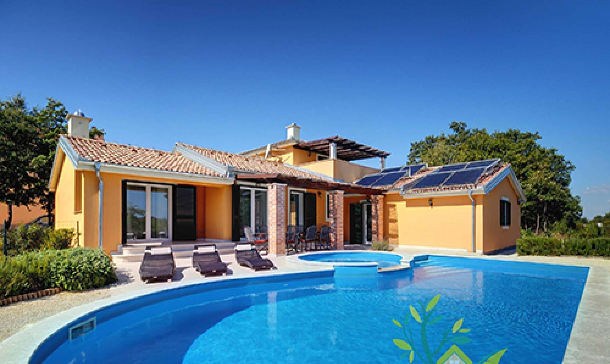 Une maison moderne dotée d’une piscine, de panneaux solaires et d’un patio avec des chaises longues.