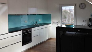 A modern kitchen with white cabinets, a black countertop, and a window with a view of trees. - Fantastic, exclusive apartment with fantastic lake and alpine views (Immenstaad am Bodensee)