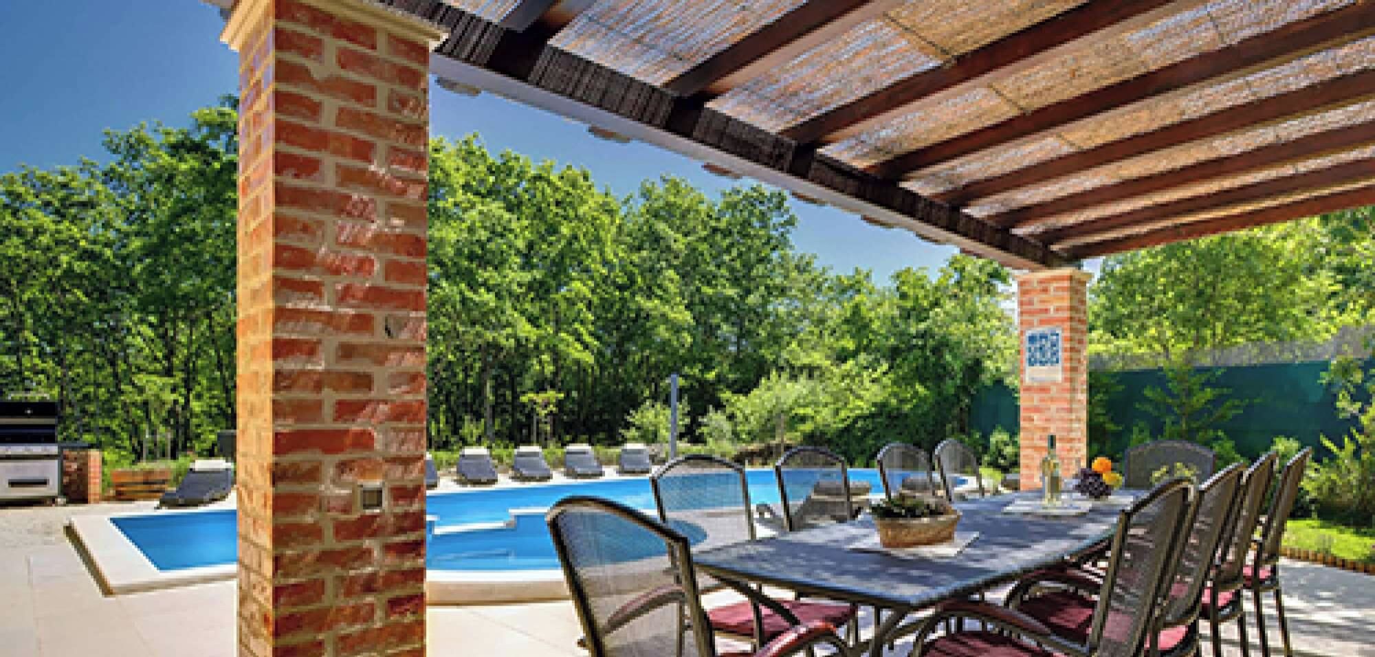An outdoor pool area with a pergola, chairs, and a table.