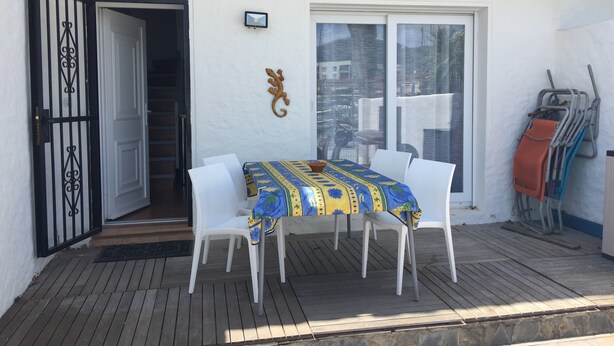 A patio with a table and chairs, a sliding glass door, a wall-mounted TV, and a set of crutches leaning against the wall. - House on port with garden-Mooring possible-Santa Margarida Rosas (Roses)