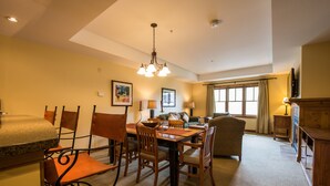 A dining area with a table set for four, surrounded by wooden chairs. There is a chandelier above the table, and a television is mounted on the wall to the right. - Near the Slopes! Bright, Modern Condo | Fireplace (Crested Butte)