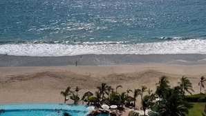 Un resort con piscina, palmeras y vista al océano.