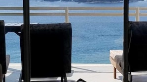 Un balcón con dos sillas y una mesa, con vistas a la costa y una cometa en el cielo.
