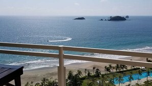 Vista al mar desde un balcón con piscina y palmeras.