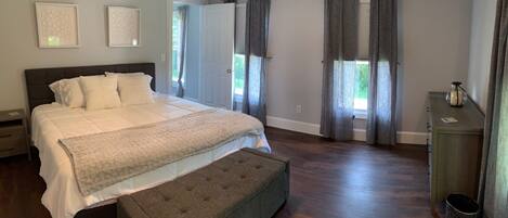A bedroom with a large bed, a bench, two framed artworks, and a nightstand.