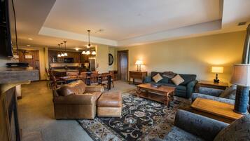 A spacious living room with a leather sofa, patterned rug, and a dining area with wooden furniture.