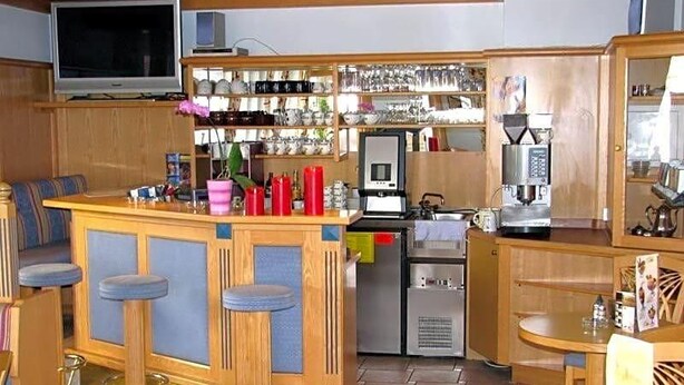 A bar area with stools, a television, and a refrigerator.