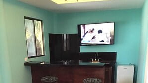 Ein Wohnzimmer mit Fernseher, zwei Barhocker, einem Couchtisch und einer Couch.