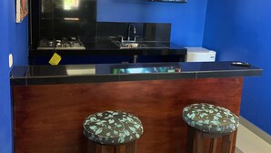 Eine Bar mit Fernseher, Spüle und zwei Barhocker.