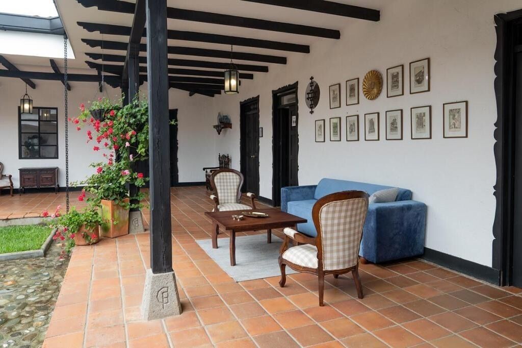 A patio area with a table and chairs, a blue sofa, and a wall with framed pictures.