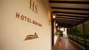 A hotel entrance with the sign "HS HOTEL BOUTIQUE" and a building illustration. - Hotel Hacienda Supracafe (Cajibío)