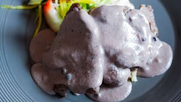 A plate with a food item covered in a creamy sauce, accompanied by a side salad.