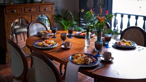 A dining table set with plates of food, glasses, and a vase with flowers. - Hotel Hacienda Supracafe (Cajibío)