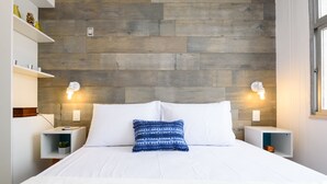 A modern bedroom with a wooden headboard, white bedding, and bedside tables with lamps.