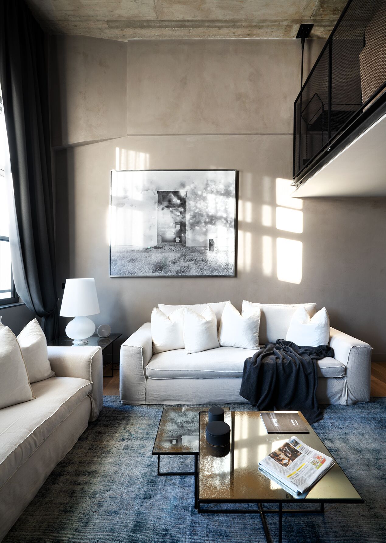 Een moderne woonkamer met een bank, een salontafel en een lamp. Op de muur hangt een grote zwart-wit foto.