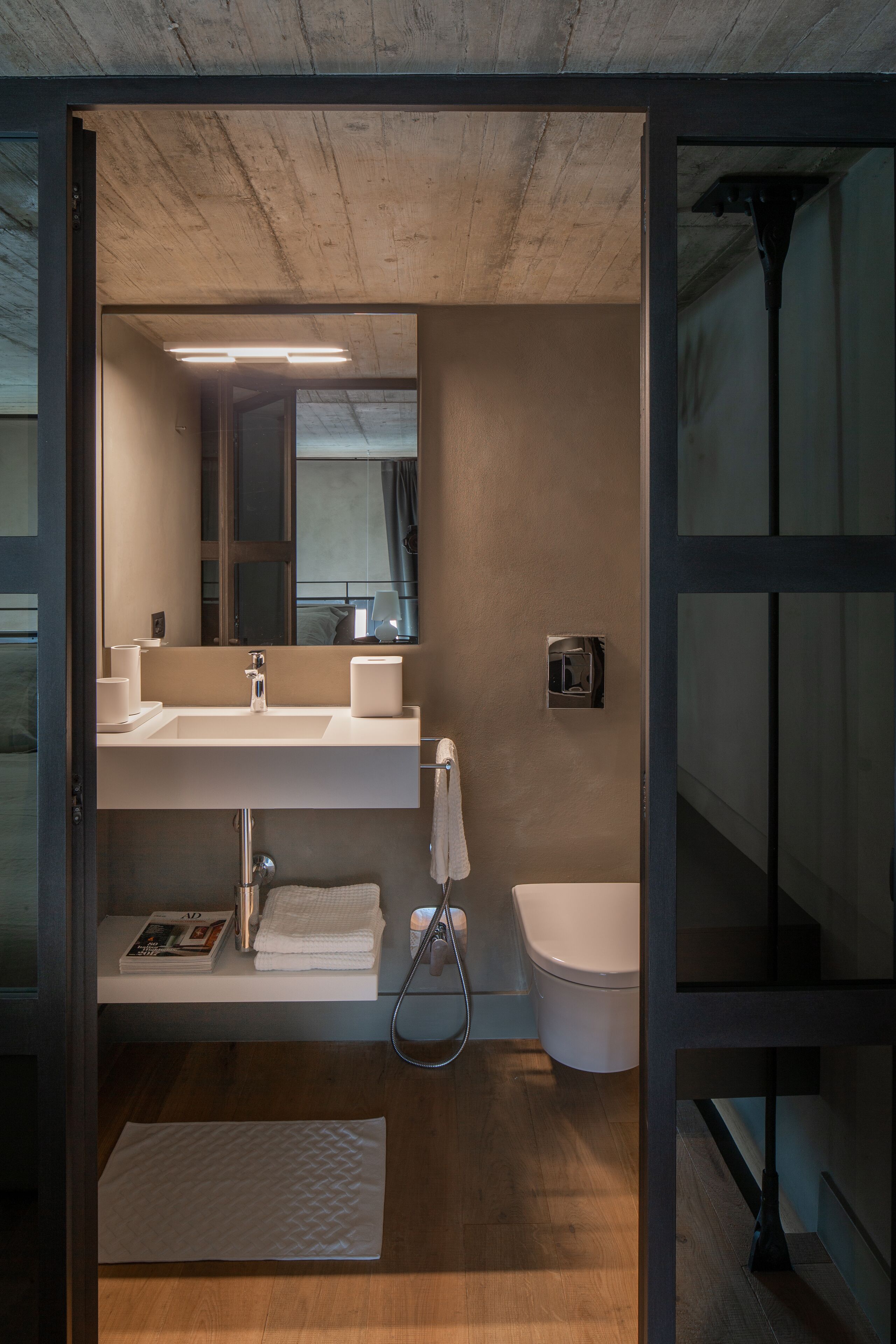 A modern bathroom with a large mirror, a sink, and a toilet.