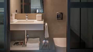 A modern bathroom with a large mirror, a sink, and a toilet.