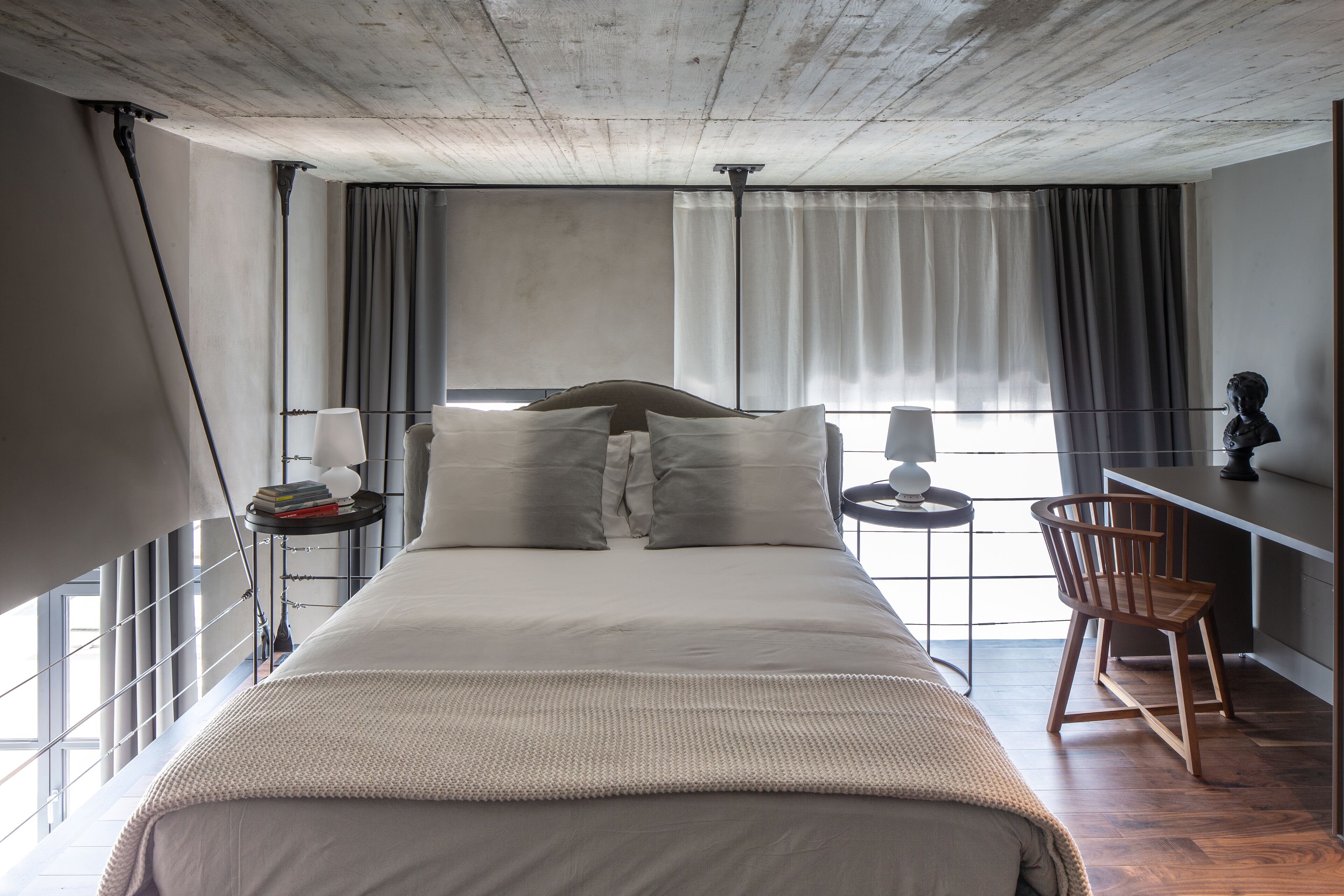 A modern bedroom with a large bed, a desk, and a chair.