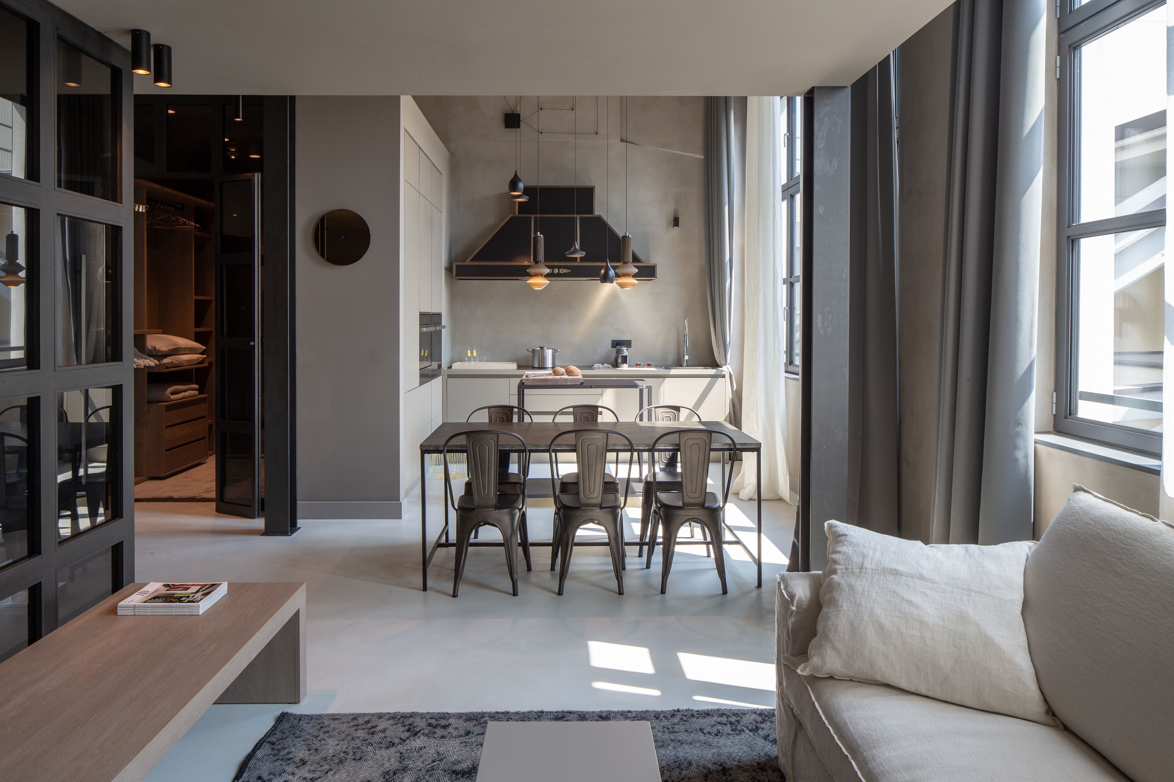 A modern living room with a sofa, a coffee table, and a dining area with chairs and a table.