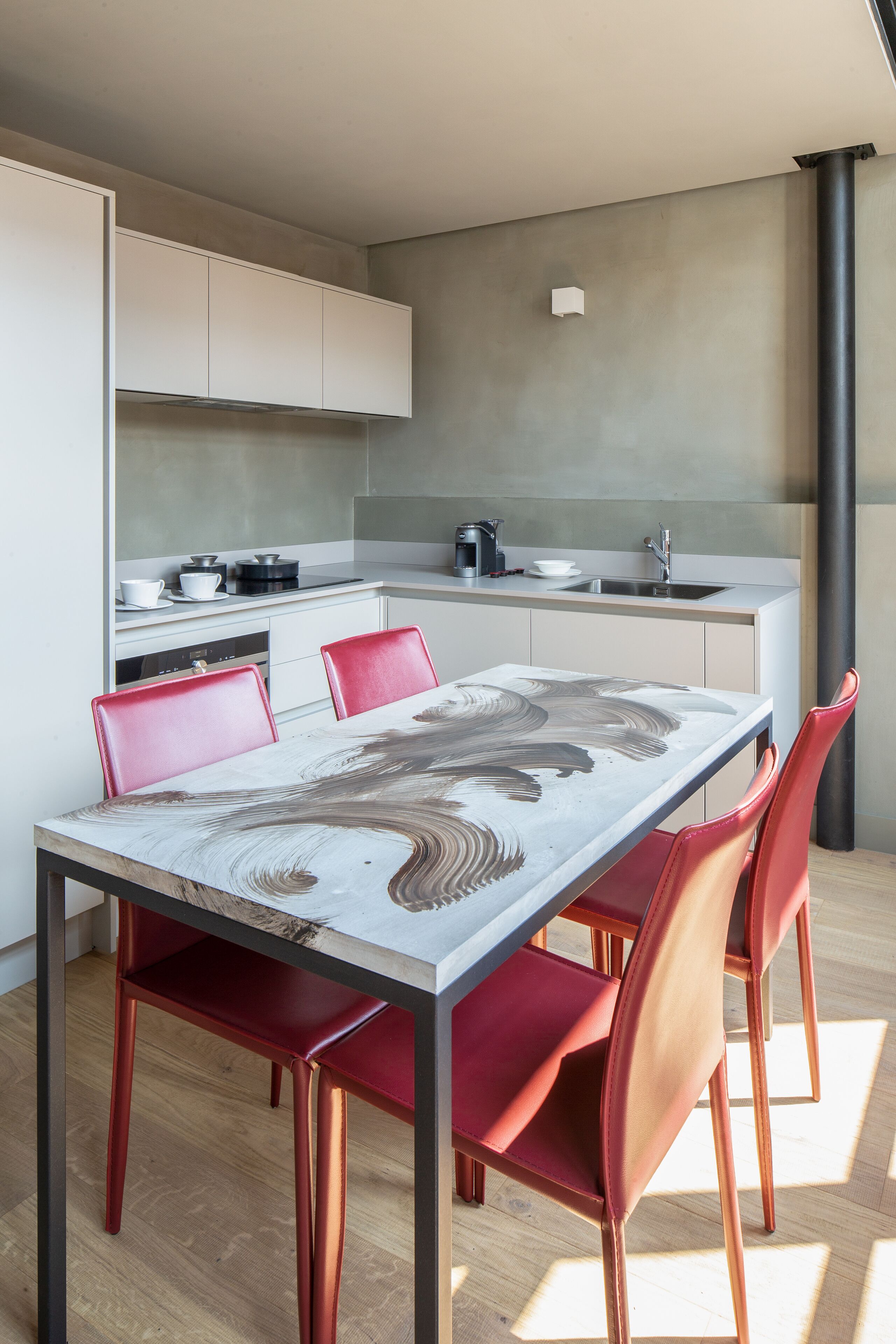 Una cocina moderna con armarios blancos, un lavamanos de acero inoxidable y una cafetera.