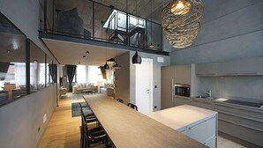 A modern kitchen with a long island, built-in appliances, and a mezzanine level with a staircase. - Edit Lofts  (Turin)