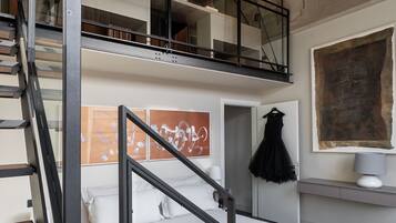 Un dormitorio moderno con una cama litera, una escalera y un cuadro abstracto grande.