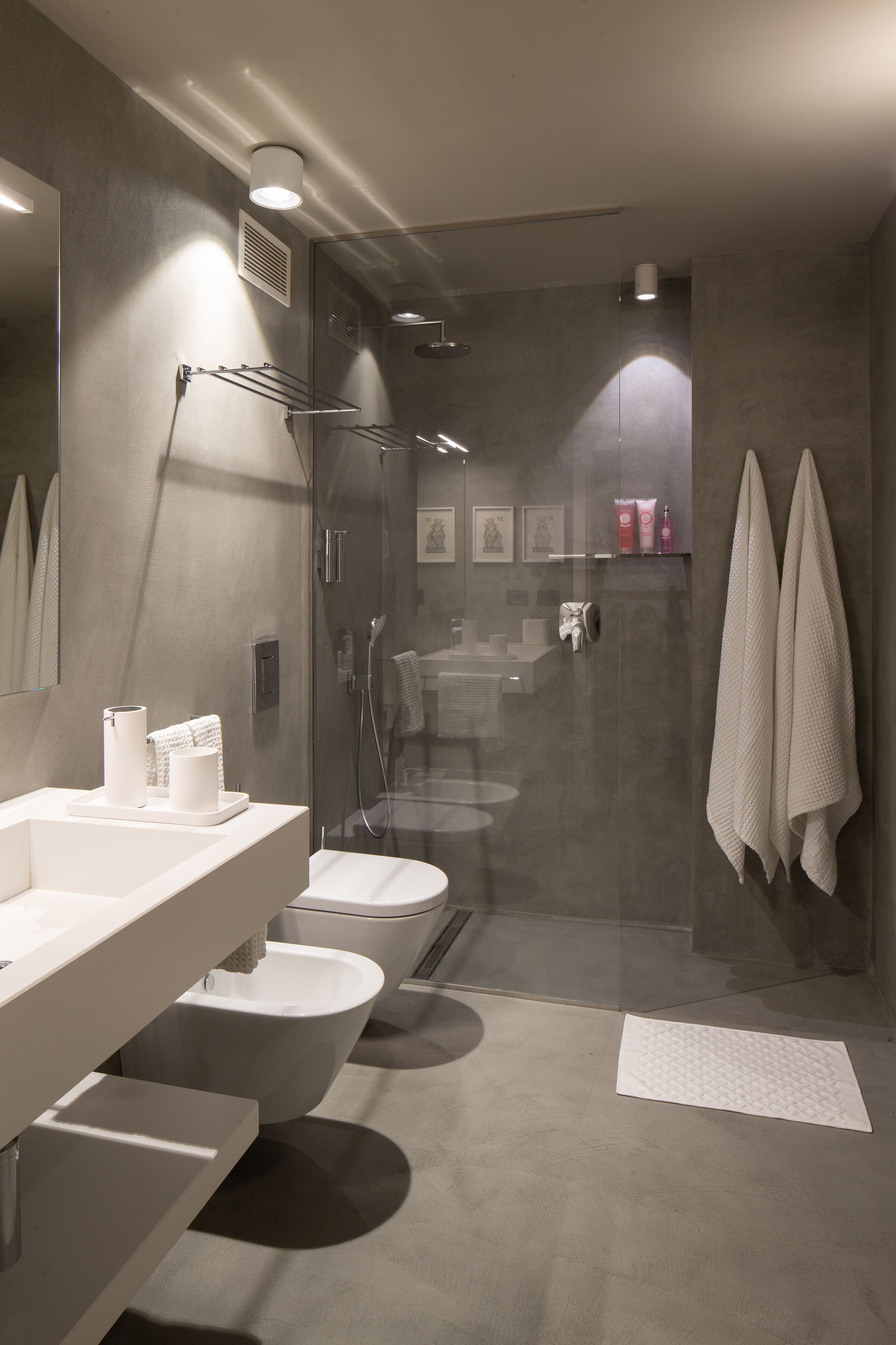 A modern bathroom with a glass-enclosed shower, a vanity with a mirror, and a toilet.