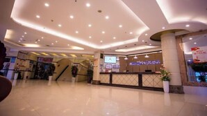A spacious lobby with a high ceiling, a reception desk, and a staircase leading to upper floors. - Crowne International Business Hotel (Shiyan)