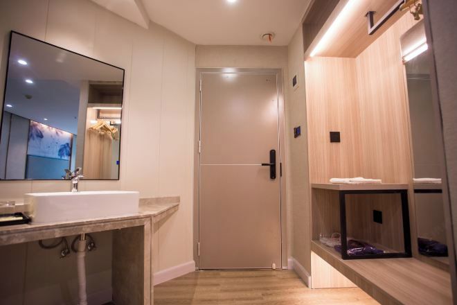 A modern bathroom with a large mirror, a sink, and a door leading to a shower area.