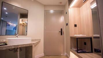 A modern bathroom with a large mirror, a sink, and a door leading to a shower area.