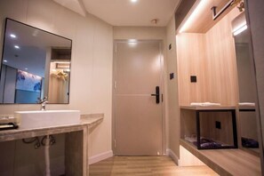 A modern bathroom with a large mirror, a sink, and a door leading to a shower area. - Crowne International Business Hotel (Shiyan)