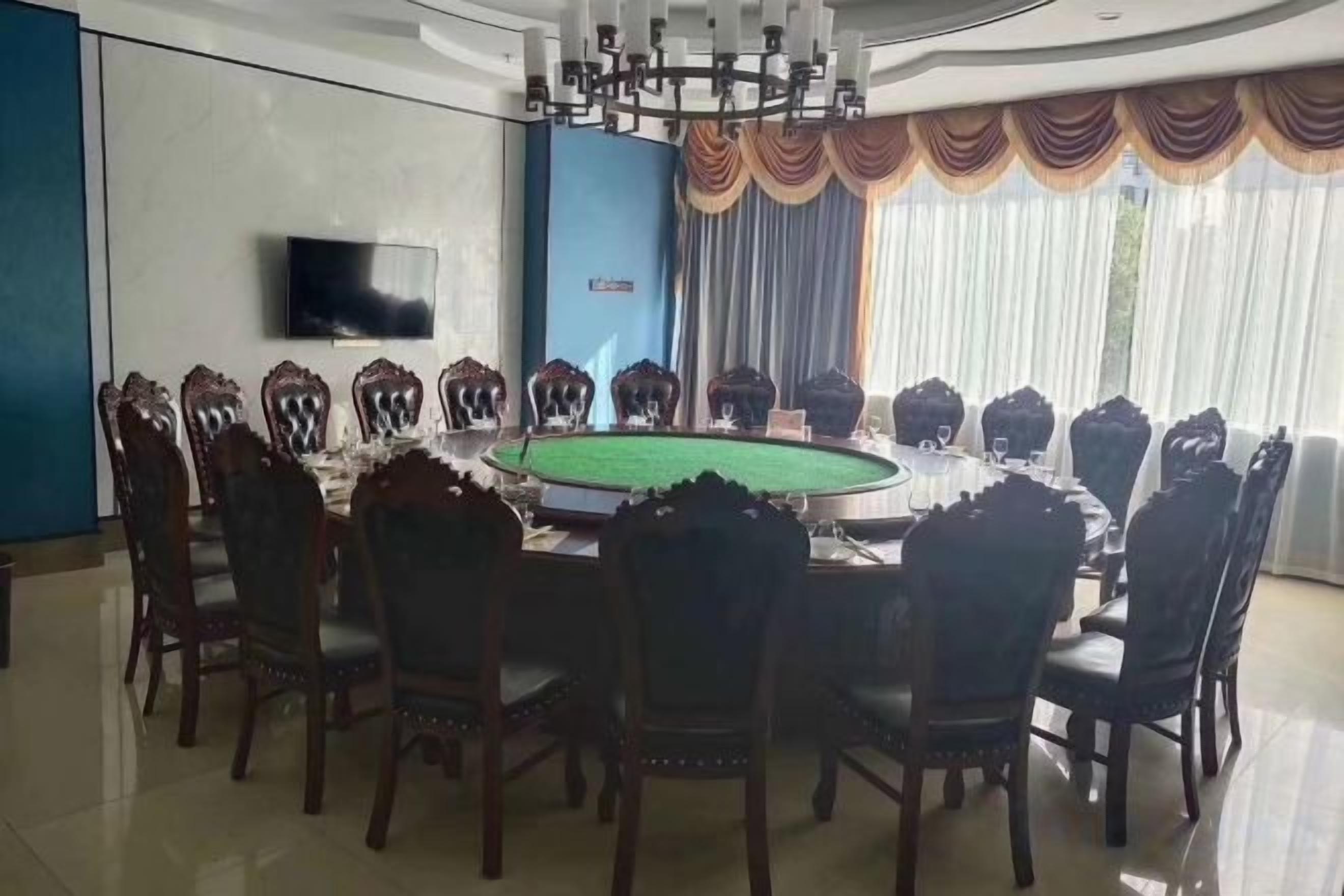 Una sala conferenze con un tavolo rotondo, sedie, un televisore e tende.