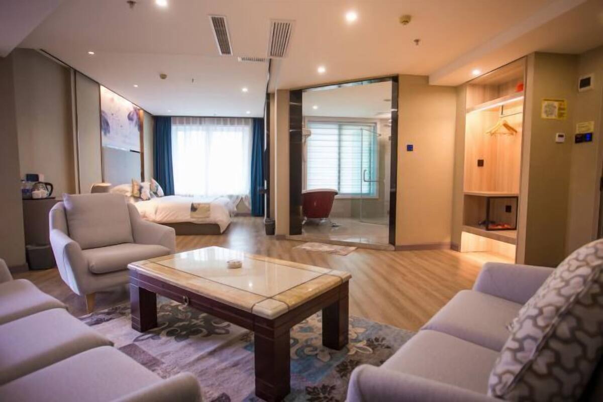 Una habitación de hotel con cama, una zona de estar con una mesita de café, un sofá y un armario.